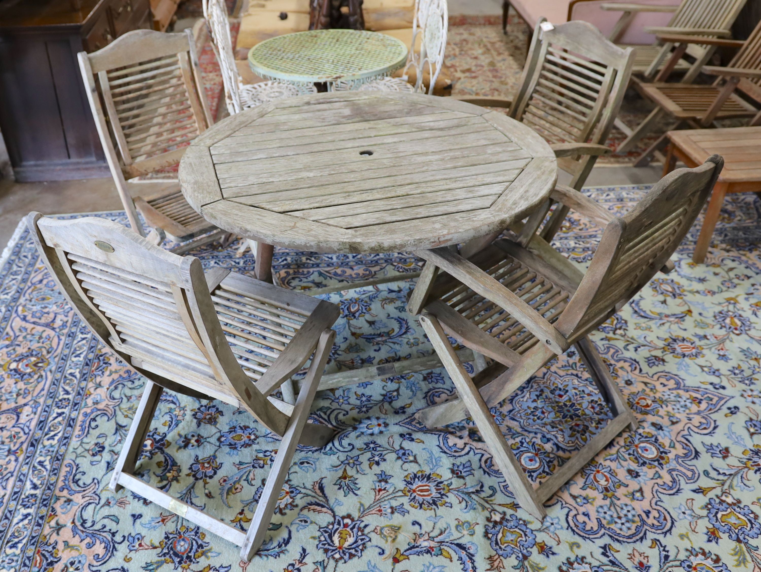 A weathered teak circular folding garden table, diameter 110cm, height 74cm and four folding chairs